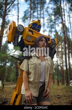 Cosplayer à l'image d'un robot transformateur et fille se tiennent ensemble parmi la forêt. Banque D'Images