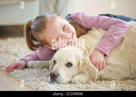 Un enfant satisfait se câlin avec un chien Golden Retriever à la maison Banque D'Images