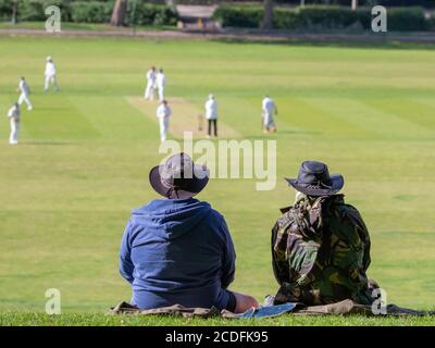 Deux personnes en chapeaux regardent un match de cricket. Banque D'Images