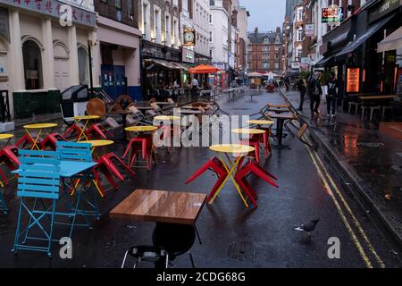 Lors d'une nuit de pluie à Soho, les tables établies pour la distanciation sociale sur Frith Street restent vacantes à un moment où les bars et restaurants récemment rouverts sont désespérés pour la clientèle pendant la pandémie du coronavirus, le 27 août 2020, à Londres, en Angleterre. Banque D'Images