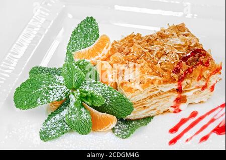Dessert traditionnel napoléon (mille-feuille) avec feuilles de menthe, glaçage au sucre, tranches de mandarine et décoration de confiture isolée sur le backgro blanc Banque D'Images