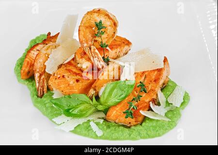 Steak de poisson rouge cuit et crevettes frites au fromage fort tranches de purée de brocoli vert sur blanc Banque D'Images