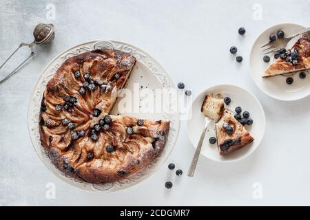 Gâteau de pomme en tranches avec myrtilles servi sur une table blanche, tiré d'en haut Banque D'Images