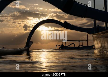 Lever du soleil sur Sanur Beach Bali. Un bateau traditionnel appelé un jukung se prépare à mettre la voile. Le rayon de lumière rend l'atmosphère du matin plus belle Banque D'Images