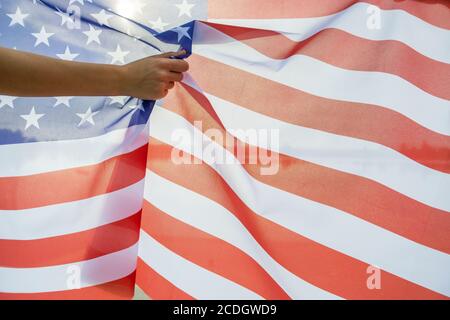 Main humaine tenant le drapeau national des États-Unis. Célébration du concept de jour de l'indépendance des États-Unis. Banque D'Images