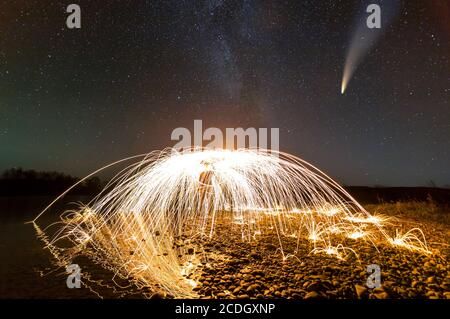 Exposition longue de laine d'acier en cercle abstrait faisant feu des averses d'étincelles jaunes avec ciel étoilé sombre de nuit au-dessus. Banque D'Images