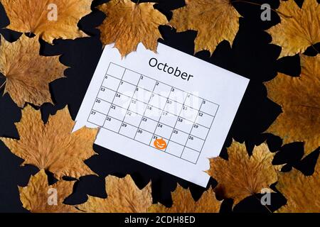 Arrière-plan de Halloween. Page de calendrier avec marque le 31 octobre et chute sur table sombre vue du dessus Banque D'Images