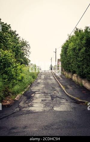 Une route droite à piste unique, le tarmac, mène vers le haut d'une colline avec des arbres des deux côtés à Consett, comté de Durham, Royaume-Uni Banque D'Images