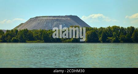 Lac idyllique avec une bande de forêt et le grand gâcher le tas d'une mine de sel en arrière-plan Banque D'Images