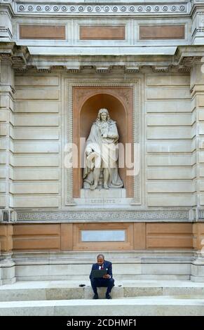 Londres, Angleterre, Royaume-Uni. Homme travaillant sur son ordinateur portable devant une statue de Gottfried Leibniz devant l'Académie royale des arts Banque D'Images