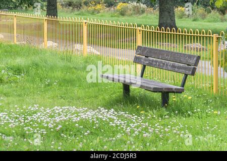 Siège public solitaire surcultivé / banc dans un terrain de jeu pour enfants vide de personnes pendant le verrouillage de Covid Royaume-Uni. Espace public déserté, banc de parc vide au Royaume-Uni. Banque D'Images