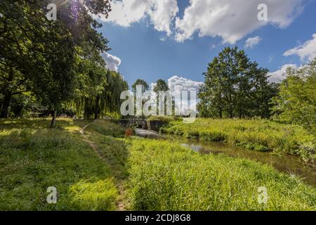 Parc municipal de Sittard avec le ruisseau Keutelbeek entouré d'arbres et végétation verte avec un petit pont au-dessus du barrage et le sluice dans le backgroun Banque D'Images