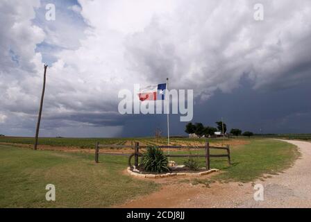 Mitchell County, TX le 26 juillet 2007 : des nuages de tempête traversent les plaines, lançant une brise raide sur le drapeau de l'État du Texas en volant à une entrée du ranch sur l'autoroute 208 du Texas entre Abilene et San Angelo. ©Bob Daemmrich Banque D'Images