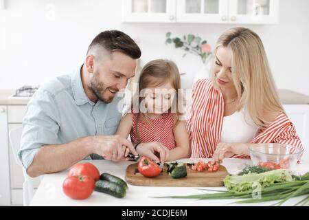 Une petite fille mignonne et ses beaux parents cuisent cuisine à la maison Banque D'Images
