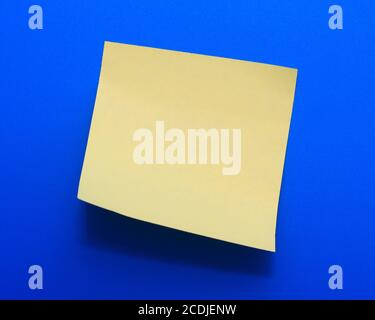 Papier note jaune sur fond bleu Banque D'Images