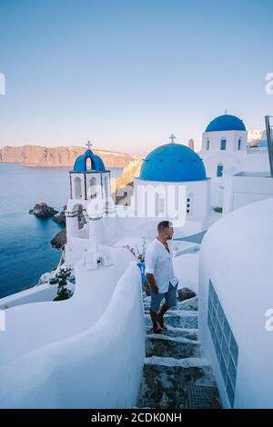 Coucher de soleil sur l'île de Santorini Grèce, beau village blanchi à la chaux Oia avec église et moulin à vent pendant le coucher du soleil, jeunes hommes en vacances de luxe Banque D'Images