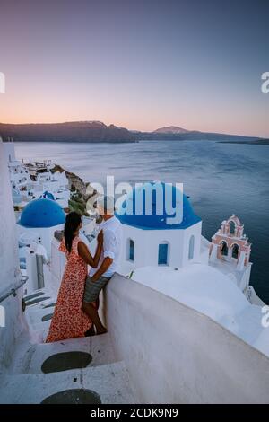 Santorini Grèce, jeune couple en vacances de luxe à l'île de Santorini regardant le lever du soleil près de l'église à dôme bleu et le village blanchi à la chaux d'Oia Banque D'Images