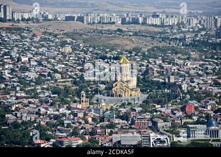 La cathédrale Sainte-Trinité de Tbilissi, vue panoramique depuis le mont Mtatsminda, avec des banlieues en arrière-plan. République de Géorgie. Banque D'Images