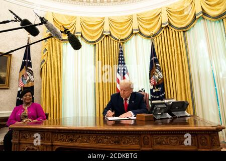 Le président des États-Unis Donald J. Trump signe le document accordant à Alice Marie Johnson, défenseur de la réforme de la justice pénale, une grâce complète dans le Bureau ovale de la Maison Blanche à Washington, DC. Mme Johnson regarde de gauche.Credit: Anna Moneymaker/Pool via CNP | utilisation dans le monde entier Banque D'Images