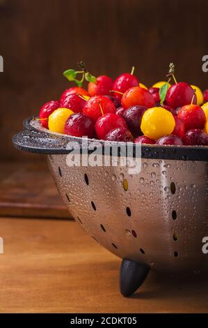 Prunes fraîches dans une passoire sur une table en bois Banque D'Images