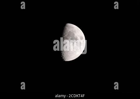 Cirage de la demi-lune dans le ciel nocturne, avec la ligne de terminaison montrant les cratères d'impact et les ombres Banque D'Images