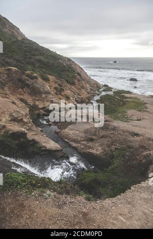 De l'eau douce coule sur la roche sombre des chutes d'Alamere à point Reyes, en Californie. Banque D'Images