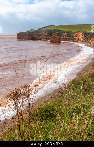 Vagues se brisant sur la plage de Ladram Bay près d'Exmouth dans le sud du Devon, Angleterre, Royaume-Uni. Falaises de grès rouge, partie de la côte jurassique. Banque D'Images