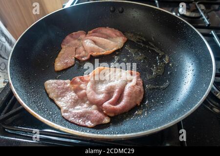 Quelques tranches de bacon cuisent dans une poêle. Banque D'Images