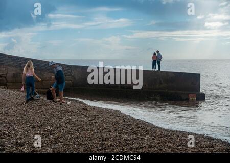 Un homme et une femme se tiennent ensemble au bout d'un mur de pierre qui jante dans la mer à Sidmouth, dans le sud du Devon, au Royaume-Uni Banque D'Images