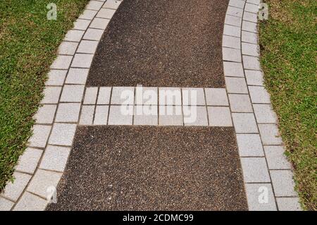 Sentier pavé et carrelé serpentant à travers un jardin à la loi. Banque D'Images