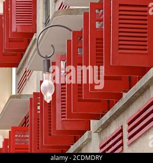 Vue latérale d'une rangée de volets vénitiens en bois rouge ouverts sur un bâtiment colonial restauré à Singapour. Banque D'Images