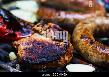 Steaks, saucisses, l'oignon, le poivron rouge et de pain grillé sur un barbecue Banque D'Images