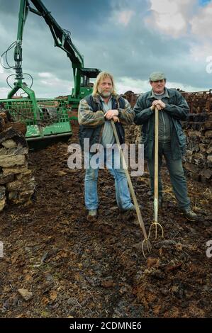 Hommes avec une fourche de chargement de tourbe, entassés de boues de tourbe dans une tourbière, la découpe de tourbe, le chargement des boues sèches avec une excavatrice sur chenilles, le stockage de CO2, Goldenstedter Banque D'Images