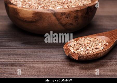 assiette et cuillère pleine de sarrasin sur fond de bois Banque D'Images