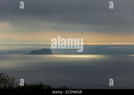 L'île de Skrypleva, où se trouve le plus vieux phare de Vladivostok, est éclairée par le soleil qui se brise à travers les nuages. Banque D'Images