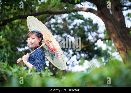 Belle fille asiatique est titulaire d'Umbrella dans la plantation de thé vert Banque D'Images