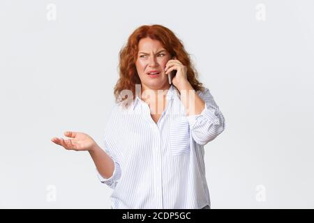 Frustrée et mécontente, confuse et grognante femme d'âge moyen haussant les épaules et craquant dégoûtée en parlant sur téléphone portable de quelque chose de terrible Banque D'Images
