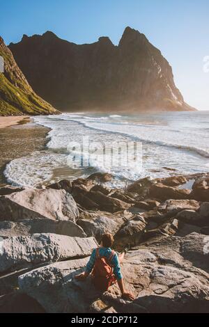 Homme touristique avec sac à dos assis sur la plage de Kvalvika en Norvège profiter de la vue sur l'océan voyage style de vie vacances d'été en plein air Banque D'Images