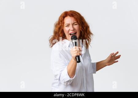 Emotions, style de vie et loisirs. Artiste féminine passionnée et insouciante, femme d'âge moyen chantant une chanson dans le microphone, chanteuse Banque D'Images