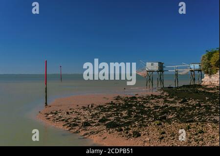 Cabane de pêche traditionnelle en bois ou cabine, reposant sur des pilotis et accessible par un passage. Littoral de l'estuaire de la Gironde à Talmont-sur-Gironde, Nouvelle-Aquitaine, France. À marée haute d'août à octobre, les pêcheurs utilisent des treuils pour abaisser puis élever leurs carrelates, filets carrés étirés sur des cadres métalliques, pour récolter des crevettes, des sardines et d'autres petits poissons. Banque D'Images