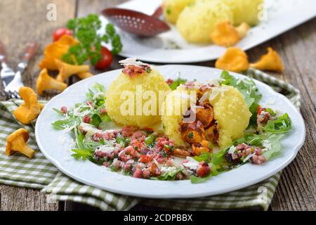 Copieux boulettes de pommes de terre farcies aux chanterelles rôties et servies avec des cubes de jambon frits au beurre, des feuilles de rucola et du parmesan Banque D'Images