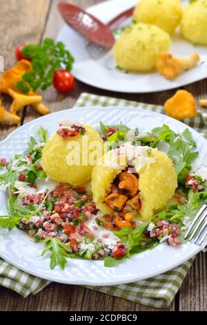 Copieux boulettes de pommes de terre farcies aux chanterelles rôties et servies avec des cubes de jambon frits au beurre, des feuilles de rucola et du parmesan Banque D'Images