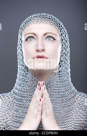 Jeune femme avec cagoule de chainmail médiéval avec les mains pliées Banque D'Images