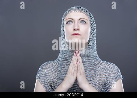 Jeune femme avec cagoule de chainmail médiéval avec les mains pliées Banque D'Images