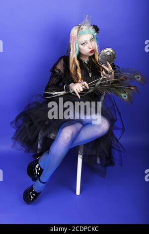 Jeune femme fantastique avec miroir de main et plumes de paon Banque D'Images