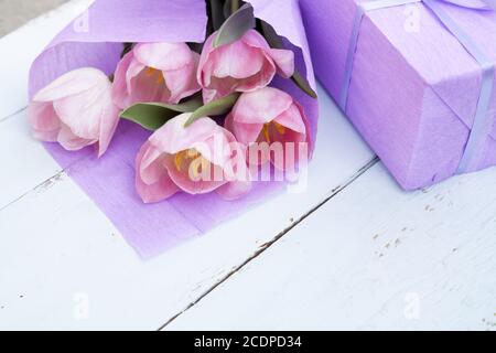 Beau bouquet de tulipes roses en papier cadeau et violet sur fond de bois clair Banque D'Images