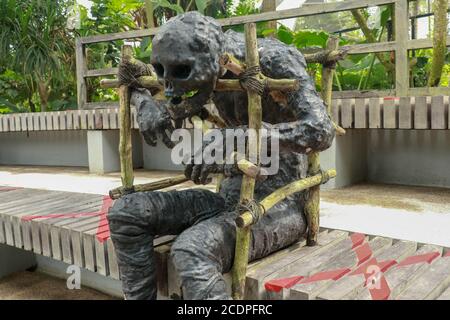 Momie recouverte de vêtements dans le crâne décoré à halloween cosplay et lumière sur fond sombre. Figure d'une momie noire assise sur un banc. Zombie dedans Banque D'Images