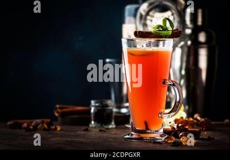 Rhum au beurre chaud, cocktail alcoolisé réchauffant l'automne ou l'hiver avec jus de pomme et de citron, rhum foncé, miel, cannelle en grand verre sur fond sombre Banque D'Images