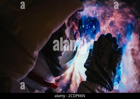 Astronaute regardant l'espace profond, la galaxie et les planètes depuis la fenêtre de sa capsule. Concept de la science et de l'exploration spatiale Banque D'Images