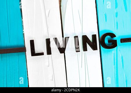 Vue isolée sur les panneaux de bois blancs, bleus et turquoise. Le mot vivant est joint en lettres noires. Banque D'Images